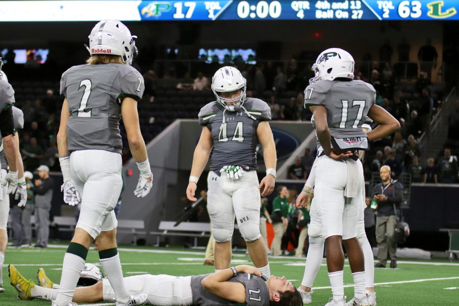 Senior kicker Cade York, No. 27, lays on the turf to reflect on his last football game as a Prosper Eagle. Fellow teammates Derien Ivy, No. 2, Aidan Sciano, No. 44, and Tyler Bailey, No. 17, gather around York. The Eagles fell 63-17 to the Longview Lobos Saturday night at The Star in Frisco.