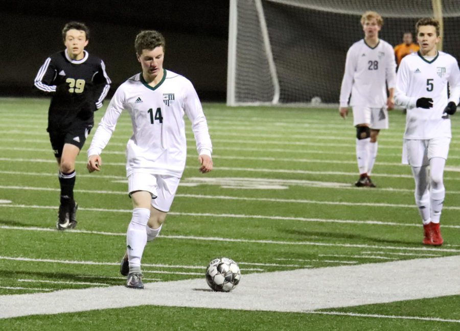 Senior Nolan DaRosa, No. 14, dribbles the ball in midfield. The boys will be looking for another win after playing Plano East. The Eagles will play Dallas Jesuit Tuesday, Jan. 29, at 7:30 p.m. at home.