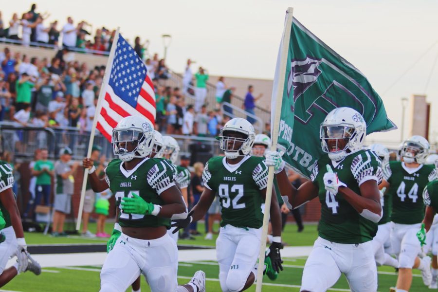 Sophomore Tyler Bailey, No. 4, runs out of the tunnel holding a Prosper flag with seniors J.T. Lane, No. 28, and Malachi Edwards, No. 92 alongside him. The Eagles beat Rowlett 31-7 in their first game of the season. They will play Keller Timber Creek Friday, Sept. 6 at the Childrens Health Stadium. 