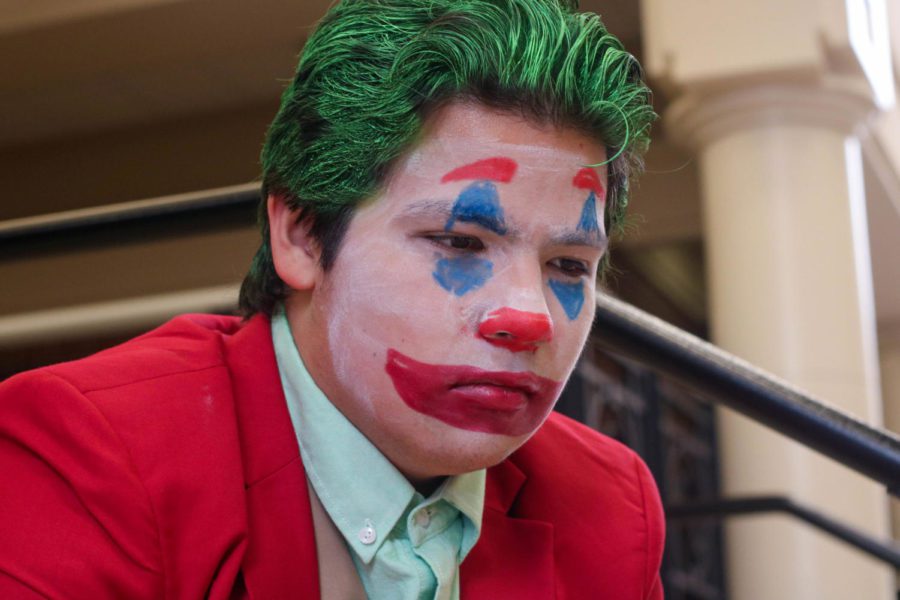 Senior Erland Merwin rests in his Joker costume near the top of the stairs in the hallway on the steps to the Auditorium on Halloween. “We live in a society,” Merwin said, quoting one of the Joker’s most famous and meme-ified lines. In this column, writer Maddie Moats highlights the many reasons for which she claims the Halloween spirit has died. 