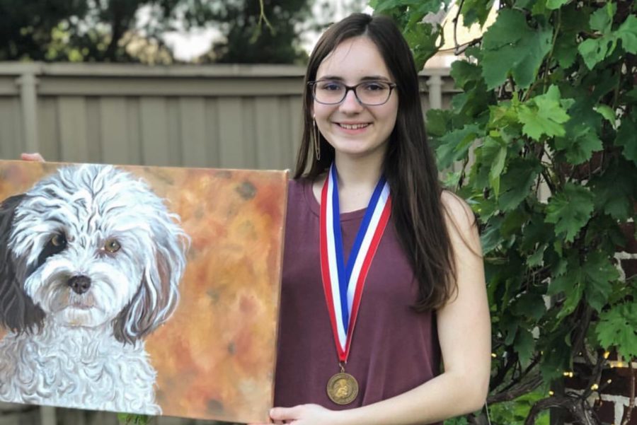 Senior Sophia Giasolli, donned with a medal won at the VASE state, holds her prize painting. That was my very first oil painting ... It is my childhood dog (Charlie), Giasolli said. In that painting, I tried to capture his eyes. I (find) that animals have really expressive eyes ... that was the main source of that painting. 
