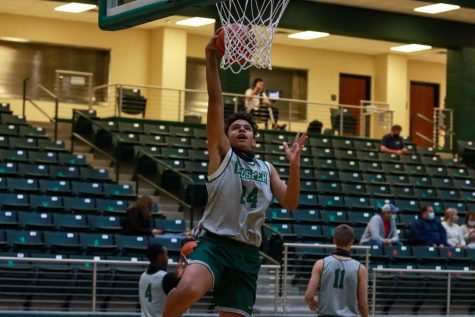 As he jumps for a basket, freshman Jaxson Ford warms up before the game. This year marks Fords first  on varsity, and he is the only freshman on the team. Ford played as a power forward during the scrimmage.