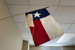 Broken and unworn, a mask hangs beside the Texas flag. Governor Greg Abbott passed an executive order March 2 lifting the mask mandate and allowing businesses to open to full capacity. With this executive order, we are ensuring that all businesses and families in Texas have the freedom to determine their own destiny, Abbott said.