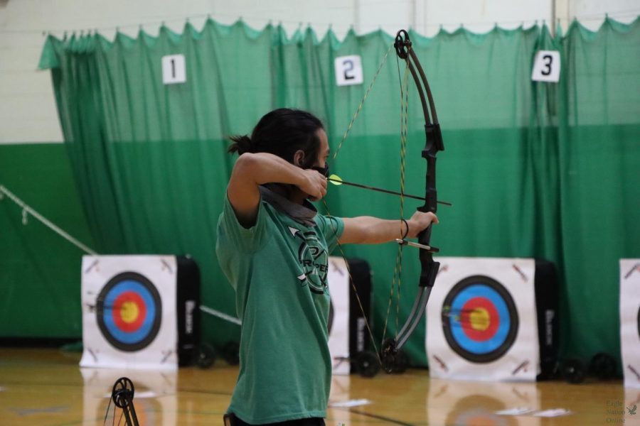 Drawing his bow, senior Ethan Doucet shoots from the 15 meter line. Doucet has played with Prosper High School archery since his freshman year. To honor the seniors during this tournament, they wore green senior shirts instead of the gray team ones. 