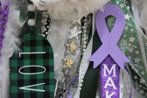 Featuring a purple ribbon, a mum sits alone. The purple ribbon serves as a tribute to senior varsity cheerleader Makayla Noble. Noble recently had spinal surgery after a mishap tumbling accident.