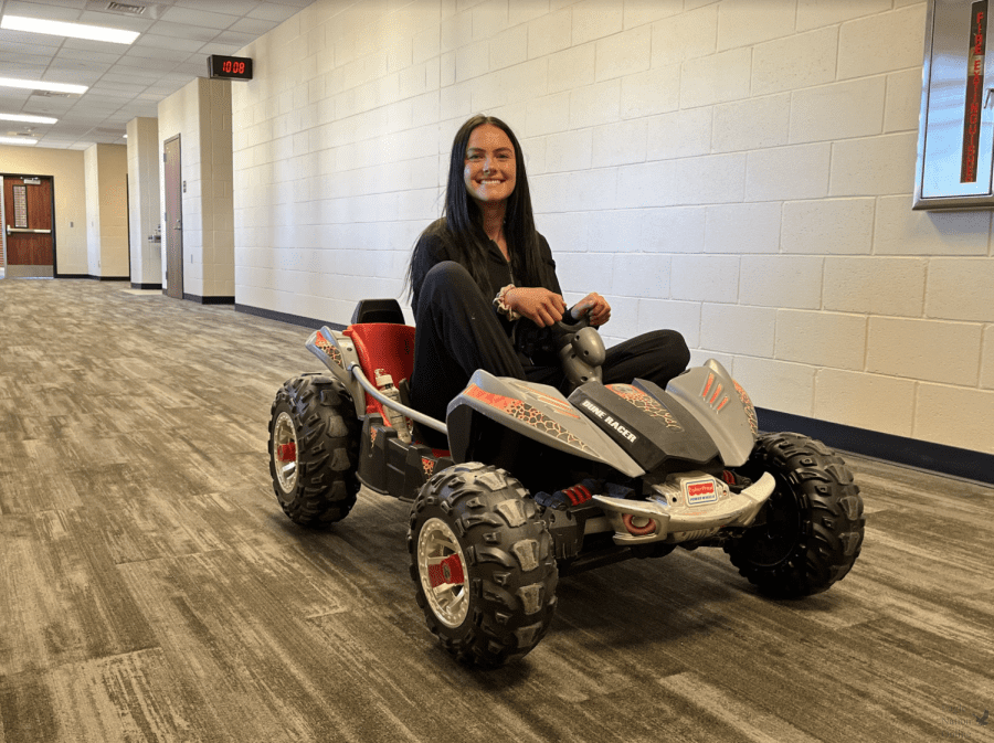 Driving a toy car, senior Riley Smith heads to second period. Students joined together Nov. 19 for “Bring Anything But A Backpack