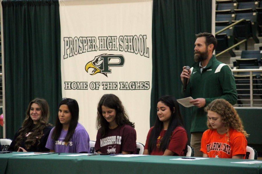 Behind seniors Aubrey OConnell, Molly McDougal, Jordyn Herrera, Ava Dinverno and Kylie Rogers, head girls soccer coach Taylor Baca talks at the Early Signing Day Ceremony. OConnell signed to run cross country at Oklahoma State University. Early Signing Day occured Wednesday, Nov. 10.