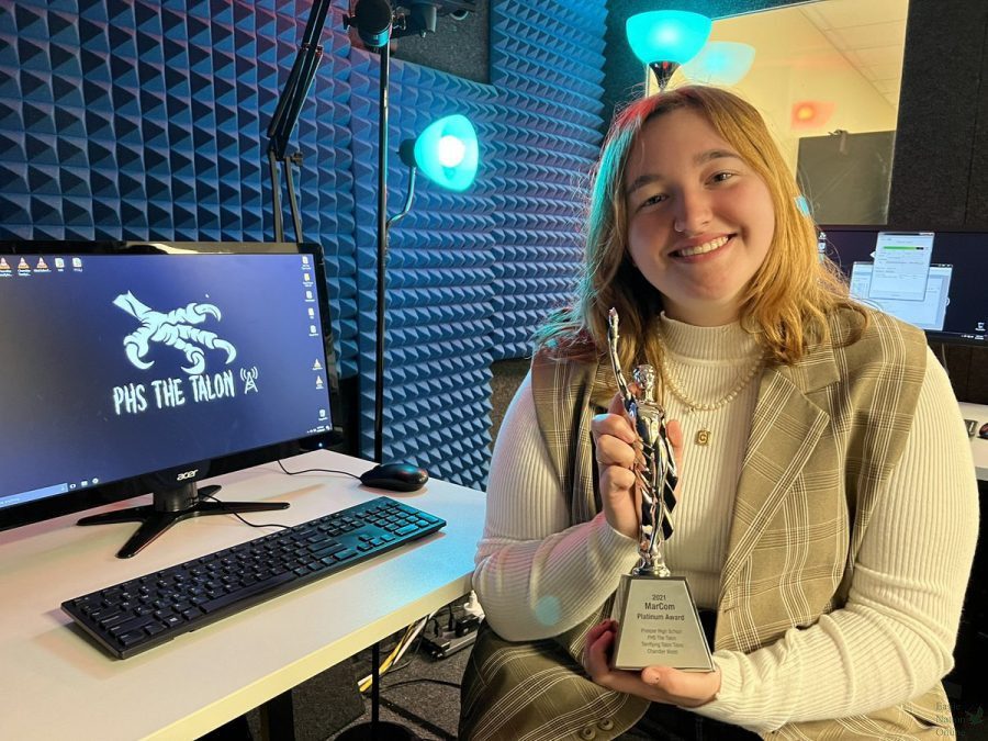 With her award, senior Chandler Webb sits in the Talon radio booth. Webb won a MarCom award for her episode in last years Terrifying Talon Tales radio series. This is the schools first platinum award.
