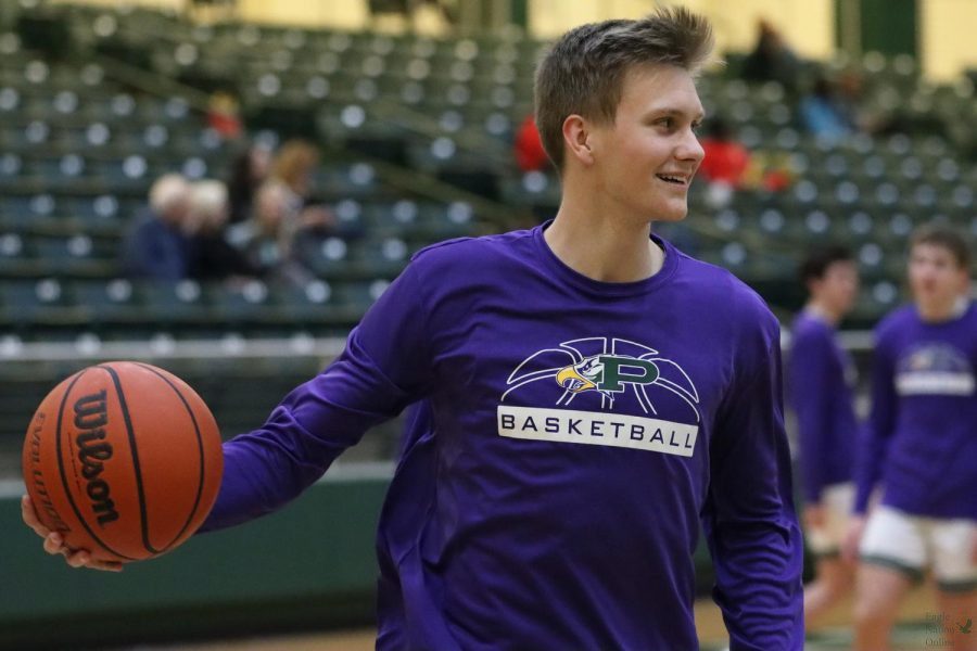Warming up before the game Feb. 8, senior Jordan Hall looks toward his team. The boys basketball teams warm-up shirts are purple in honor of junior Makayla Noble. The next boys basketball game will be Thursday, Feb. 17, at Braswell.