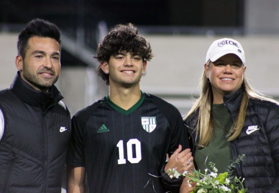 Surrounded by his parents, senior Gavyn Rosales looks out at the crowd. Senior night occurred at 7 p.m. before the game, which started at 7:30 p.m. After the game, a slideshow was shown of the seniors and their baby pictures.