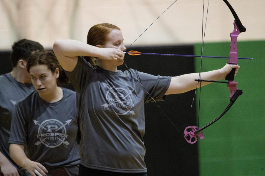 Pulling back her bowstring, Addyson Oliver aims her arrow at the target. Archery competed in the Prosper tournament on Saturday, Feb. 26. The tournament was held at the administration building which is where the team also practices. 