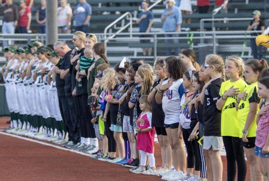 Lined up, youth softball players, coaches and members of the varsity softball team stand for the national anthem. The team played McKinney Boyd on Friday, April 22. This  game happened youth night, which honored younger, elementary school softball players. 