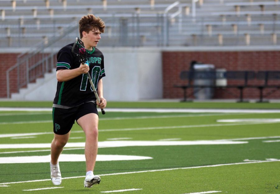 Running down the field, junior Jack Deaton holds the ball in his lacrosse stick. Deaton plays as a middie. The boys and girls lacrosse teams played each other Friday, April 15, in a charity game.