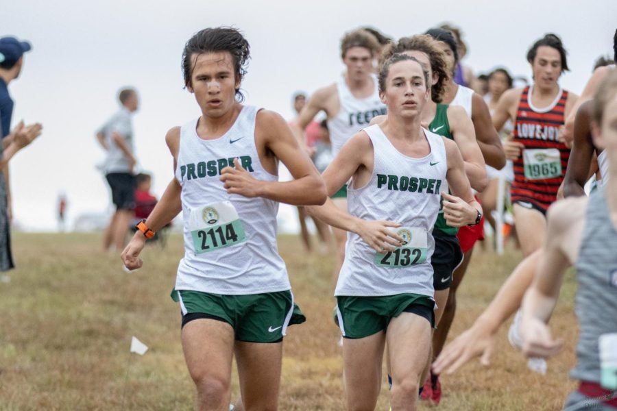 Legs extended, senior Diego Donald and junior Max Miller run past their opponents.  Donald ran a time of 16:19.00. Varsity Elite boys finished 3rd out of 33 teams. 