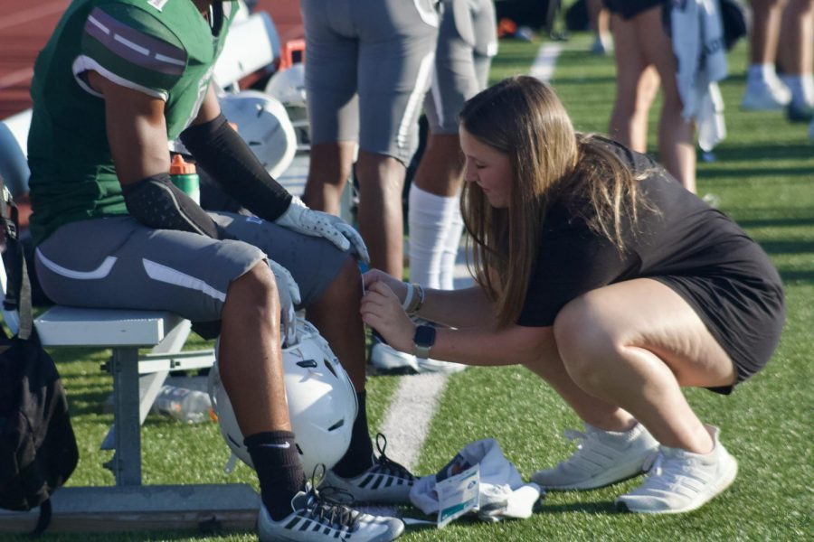 Above, Junior Mckenna Clark assists a junior varsity football player during a game as she assesses his wound. In addition to medical and therapeutic knowledge, students use communication skills to work with the athletes that need them. Id say its rewarding, sophomore Nixon Rigoni said,  (When) you know that youre helping someone be the best them.