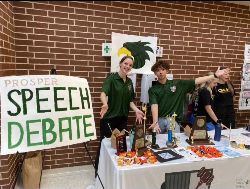 Before+the+club+fair+begins%2C+juniors+Elizabeth+Gijsbertsen+and+James+Kim+stand+at+the+Speech+and+Debate+booth.+Kim+holds+the+president+position+of+the+debate+team+and+Gijsbertsen+is+the+historian.+They+booth+handed+out+flyers+and+candy+with+information+on+signing+up+for+the+debate+class+or+joining+the+Speech+and+Debate+team+as+a+club.+
