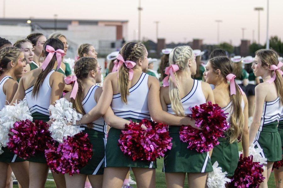 Before running down the field, the varsity cheerleaders get into a huddle. The cheer team is led by Cameron Jones and assisted by Emily Allen. The cheerleaders had pink bows and pom-poms to honor the pink out theme. 