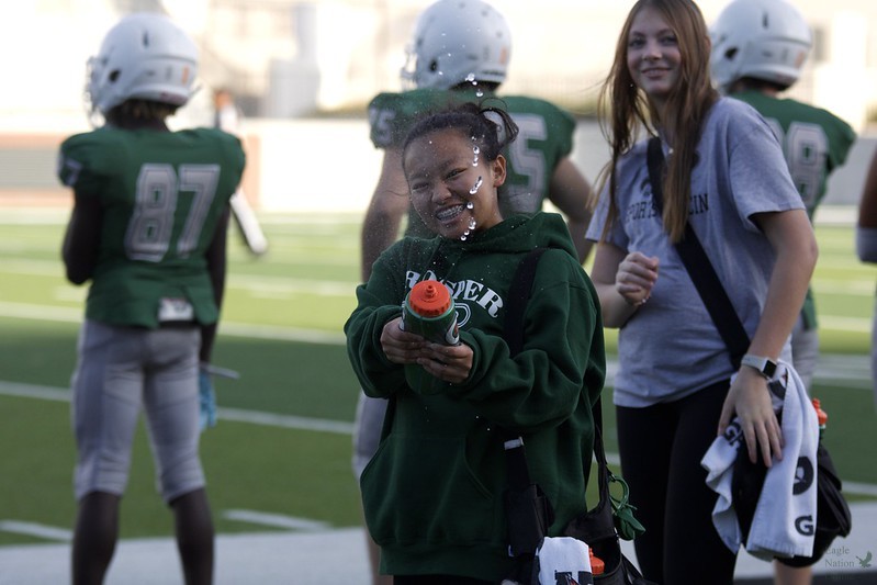 As the water squirts out of the water bottle, sophomore Mia Bedell smiles for the camera. The people around me like the photographers, Bedell said. Make my job really fun.This is Bedells first year on the field as a trainer.