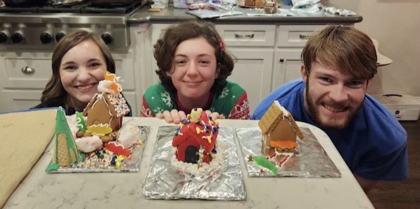 Crouching behind the counter, junior Lauren Clayton and seniors Nora Vedder and Alex Drum sit behind their entries for a family-friend gingerbread house competition. Competitors spent just about an hour on entries and voted on the top three houses. I had a lot of fun making my house, Vedder said. I always watched A Charlie Brown Christmas when I was little, so when we decided to do the competition I knew I wanted to do Snoopys doghouse. 