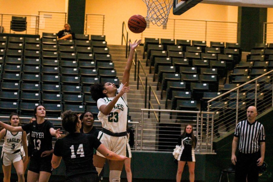 Arm extended toward the ball, sophomore Ava Scott attempts to throw the ball in the basket. This is Scotts second year playing basketball for Prosper. This is the teams second time playing Guyer this season.