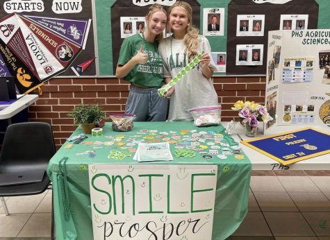 Standing at a table featuring the club, seniors Ava Anderson and Rachel Price show off stickers. The two are leaders of the club Smile Prosper. Smile Prosper provides a place where everyone feels safe, senior Ava Anderson said. Through each meeting and event, we establish dependable relationships with each other and have the security to express any repressed struggles or feelings. The stigma surrounding mental illness is so prominent in todays world, and our high school. Smile Prosper allows us to join in the fight to break down that stigma – one day and one person at a time.