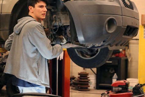 As he works on a 2005 Ford Escape, senior Michael Vasquez looks toward Alexander Bourqe. The vehicle is suspended in mid-air.  “It really makes you appreciate the hard work that goes into vehicles, Vasquez said. “How they work and get you from point A to point B.”