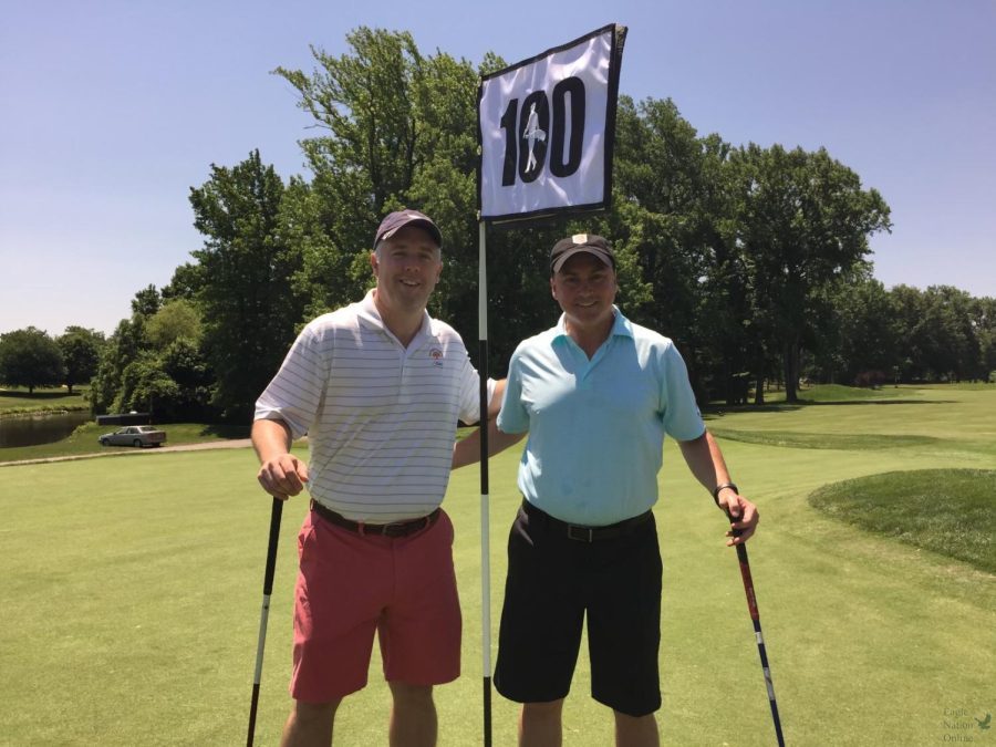 Standing with the 100 Hole Hike flag, Kevin Vedder and Chris Bartoli hold their golf clubs in between holes. Vedder first participated in the hike challenge to raise money for the Els for Autism foundation in 2013 with Bartoli joining him on his journey. Vedder partook in the challenge for 7 years in honor of his son, Seamus, who is autistic. 