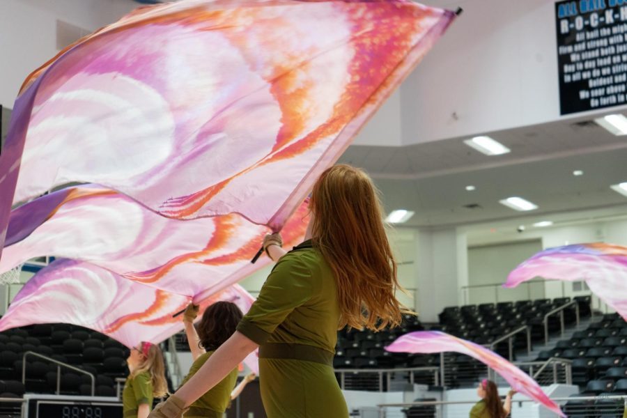 Members of the winter guard spin pink, orange and red flags. Under the direction of Lindsay Kusmierczak, varsity and JV winter guard have concluded their seasons. I joined color guard in the beginning because I heard of how close the community was. Not only within our guard but in others too,” freshman JV member Klarissa Warren said. “Every guard connects on a certain level and the amount of long lasting friendships Ive made thanks to guard this year is crazy to me.”