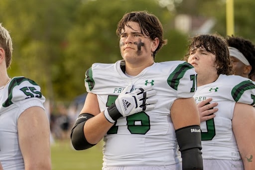 Hand on heart, senior Tyler Mercer stands with his team during the national anthem. Mercer committed to Tulane University to further his football career. In the attached article, Mercer reflects on his high school football career and decision to graduate early.