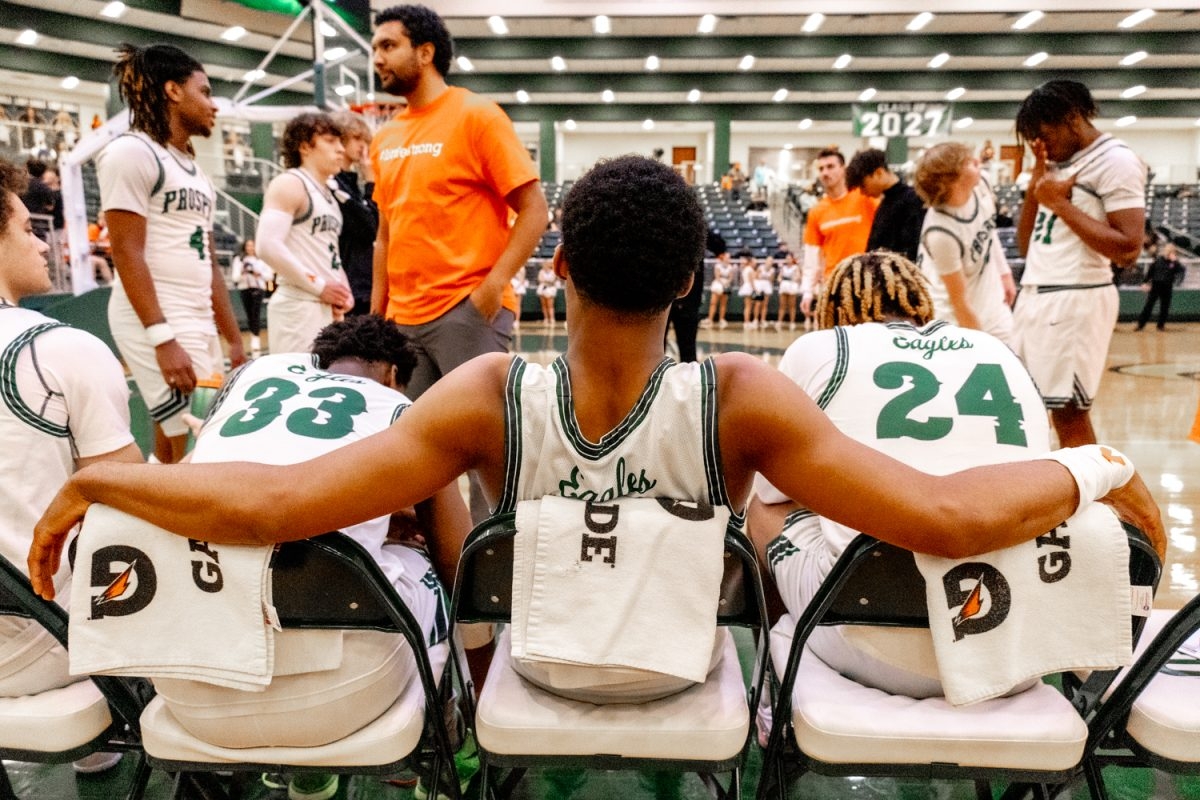 Arms extended on the back of the chairs, junior Chase Dixon awaits the starting lineup to be announced. Dixon plays as point guard. The game, which was scheduled to start at 7:15 p.m., experienced a delay due to the varsity girls game running longer than expected.