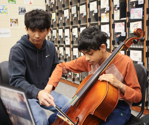 At a United Sound rehearsal, violinist junior Edwin Varghese assists freshman Prahlad Vijayaraghavan in playing the cello. The United Sound program allows students with disabilities to be mentored by fellow students in fine arts. "United Sound benefits our orchestra in a way that they can use a skill set they know to give back to the school community," Orchestra director Monika Bartley said. "So, it works on leadership skills and communication skills because, with our United Sound students, the same type of communication doesn't always work, and you might have to explain it in a different way. It really makes our students think outside the box."