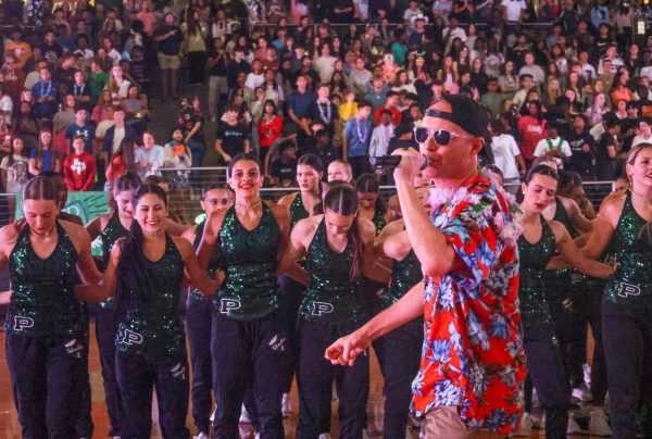 In front of the Talonettes, Principal Nick Jones speaks to the audience through a microphone. PHS hosted an aloha-themed pep rally Friday at 11:49 a.m. in the Arena. The varsity football team will play against Westlake at 7 p.m. on Thursday.