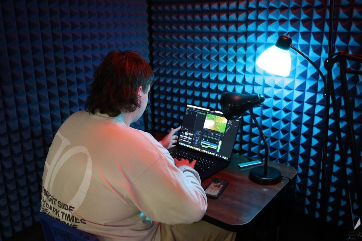 Lights shines off junior Colton Boston   as he works on a football package for ENO. The radio station allows Eagle Nation News to use the radio booth, Michael Hatch advises both programs.