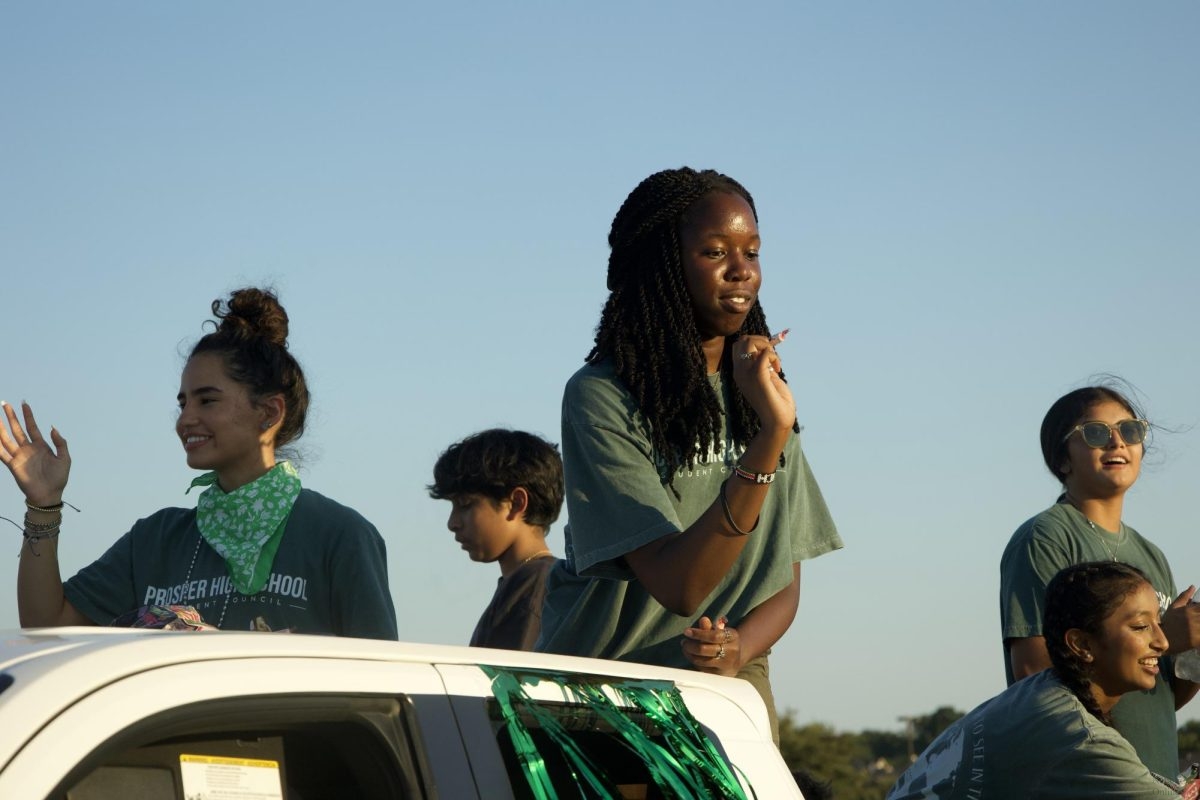 Senior Everlyn Omandi (right) throws candy from the Student Council float with senior Tatiana Henao (left). "Being apart of the parade was amazing and seeing everyone come out was exciting," Omandi said. "I had fun seeing all the families come out to support Prosper's clubs and sports. I will definitely miss this when I graduate." 