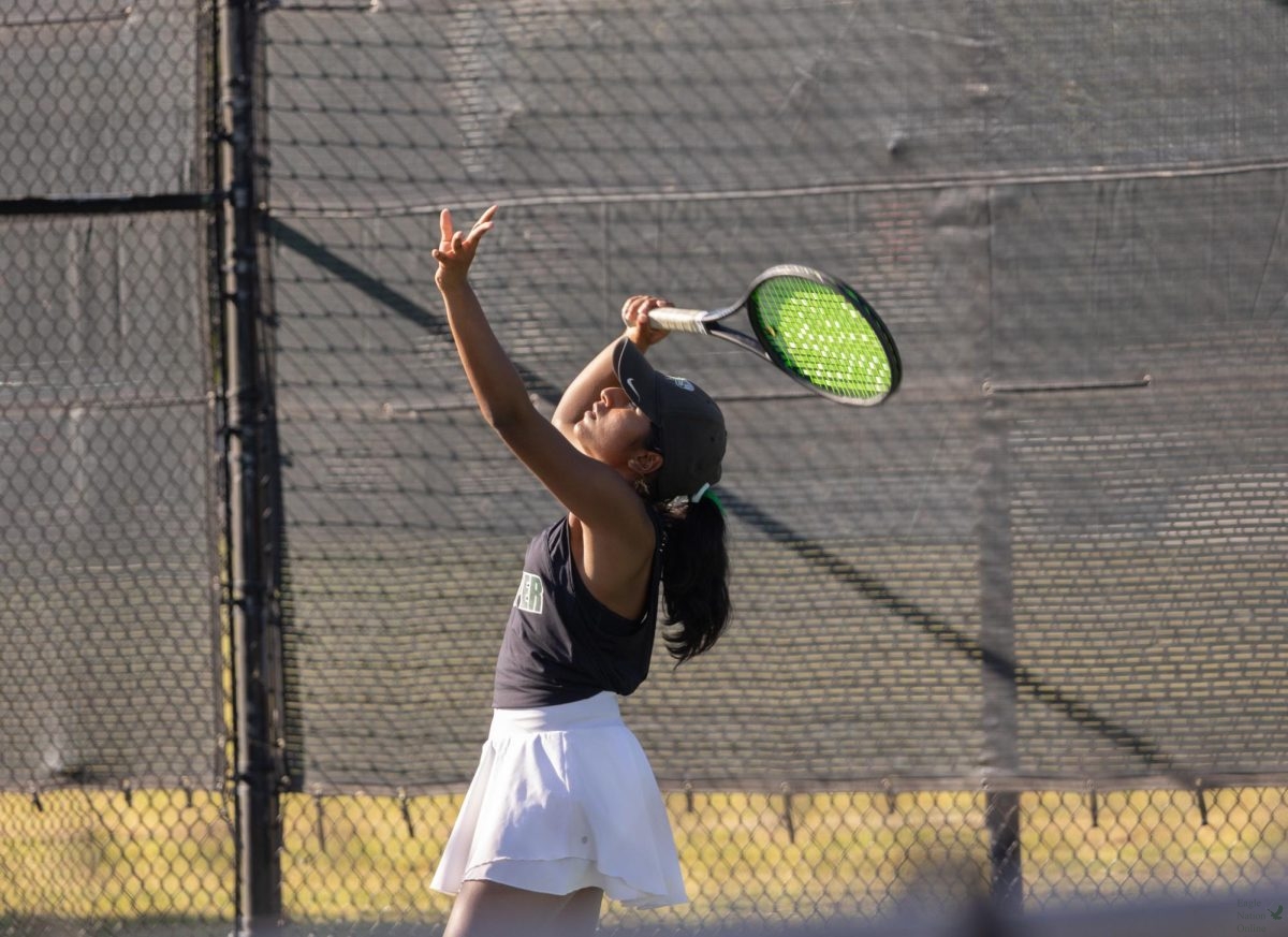 Throwing the ball up, senior Catherine Biju prepares to serve. Biju played along side her teammate senior Gaby Nielsen. "When I step on the court, I feel excited  and a bit nervous," Biju said. "You never know what is going to happen in the match, so it can be nerve wracking to compete. Yet the challenge and working toward a goal makes it really fun."