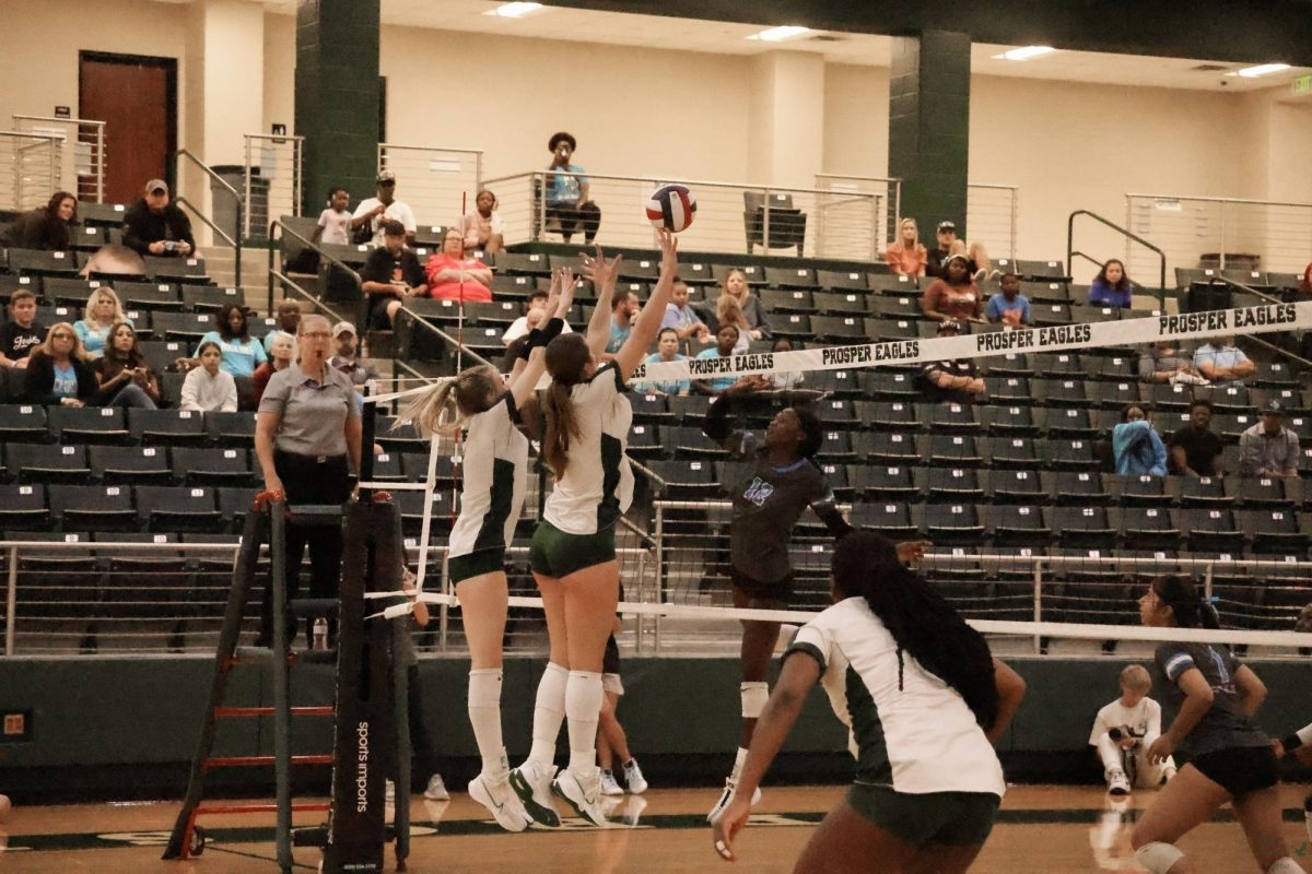 Beside her teammate, senior Camilla Cox jumps up into action, blocking a spike from Rock Hill. Her fast reaction helps keep the game in their favor. The team cheers as they build momentum.