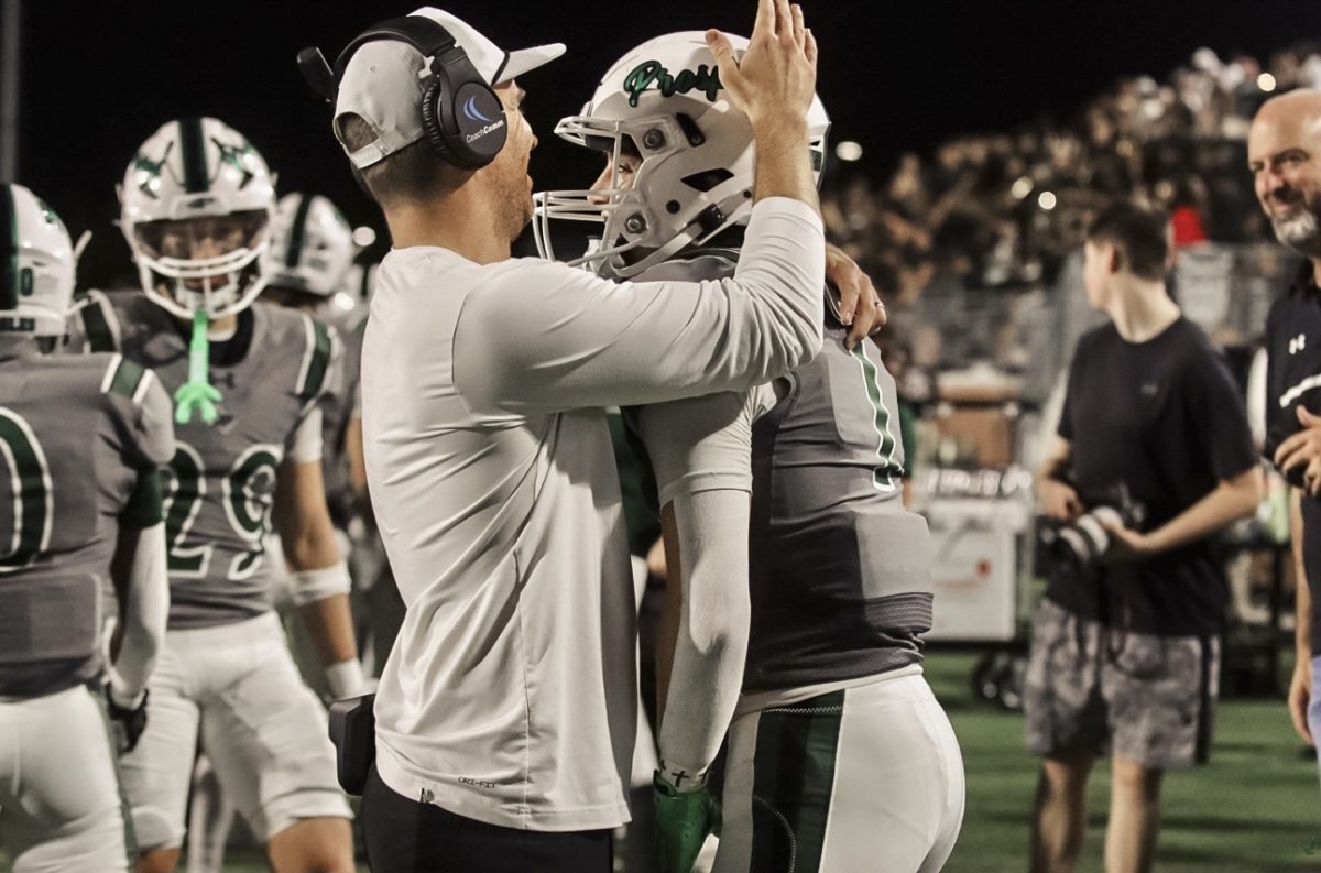 Hand on helmet, head coach Tyler Moore congratulates junior Lathon Latiolais on a successful play. Latiolais caught four passes at Friday's game and totaled 103 yards. "We just went out there and do what we do," Latiolais said. "Defense and offense went out there and did their job so we played a great game and it showed."