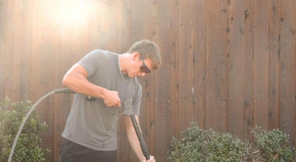 Power washing tool in hand, senior Eli Heintz cleans a sidewalk. Heintz has owned his business Rapid Renew Exterior Cleaning for over one year. Rapid Renew offers services such as power washing, window cleaning and driveway cleaning.