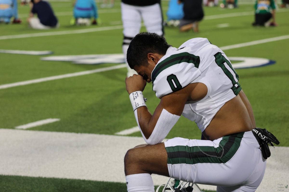 Kneeled to the ground, senior Leo Anguiano prays on the sideline before the first quarter starts. He earned the title "Offensive MVP" for this game, along with several others. The game was broadcast on WFAA channel 8.