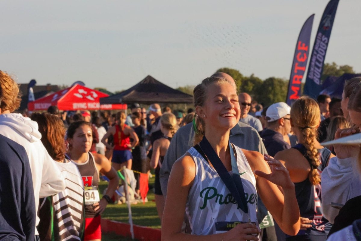 As she holds her medal, senior Regan Reed laughs with family and friends. Reed finished in 17th place on the varsity girl's team. The teams run the UIL 6A–District 6 meet tomorrow. 