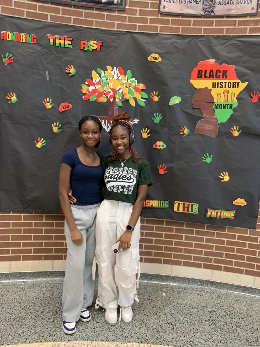 Posing in front of the Black History month sign, BSU president Racheal Fakunle and her little sister, Christiana Fakunle smile for the camera. They both attended a Black History Gallery Walk held at Rogers Middle School, Feb. 8. The gallery walk consisted of a long hallway decorated with things about Black history. 