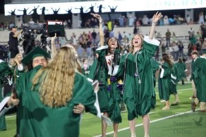 Celebrating their graduation, seniors Nora Ryan and Ava Garretson wave at their families and friends in the bleachers. Ryan plans to attend Sam Houston State University and major in health sciences. She is most proud of being the 2025 UIL state champion in the 800-meter event in track and field.