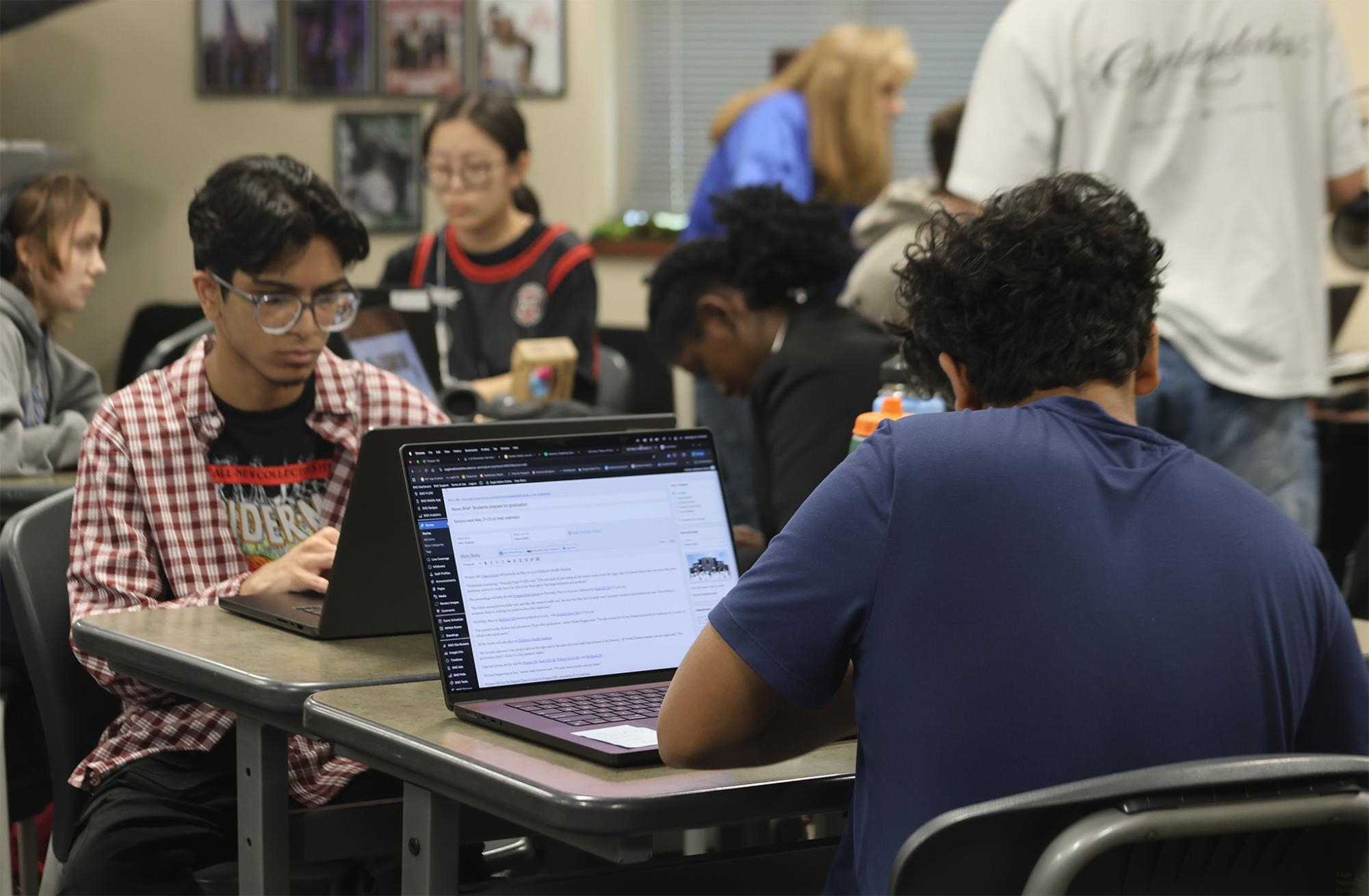 Focused on their Macbooks, senior, ENT Editor-in-Chief Yousuf Ali and sophomore, reporter Agnipravo Ghosh produce work in the ENO classroom. In the photo, Ghosh can be seen editing the news brief about graduation. The event will take place on May 21, 2026, at 9 a.m. with Ali being one of the ENO staff members that will graduate.