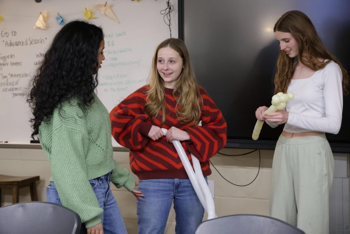 Standing in a group together in the front of the class, seniors Nicole Horak and Khyati Khanderao watch and learn from senior Isabella Hoye about how they will make the balloon animal assigned that day. The three are the only members in Balloon Animal Club, other than the club advisor Emily Koonce. "I like the joy this club brings and that we get to have fun," senior Nicole Horak said. "I'm a beginner, so I stick to cats, pigs, and dogs, but my favorite balloon animal are the flower animals."