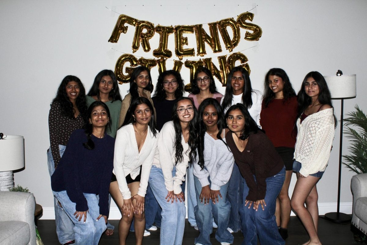 Posing for a picture, a group of friends gather around a 'Friends-giving' banner. "I love the trend of 'Friends-giving," senior Aarushi Rana said. "It's a beautiful way to give back to the people you love most, while also enjoying great food."