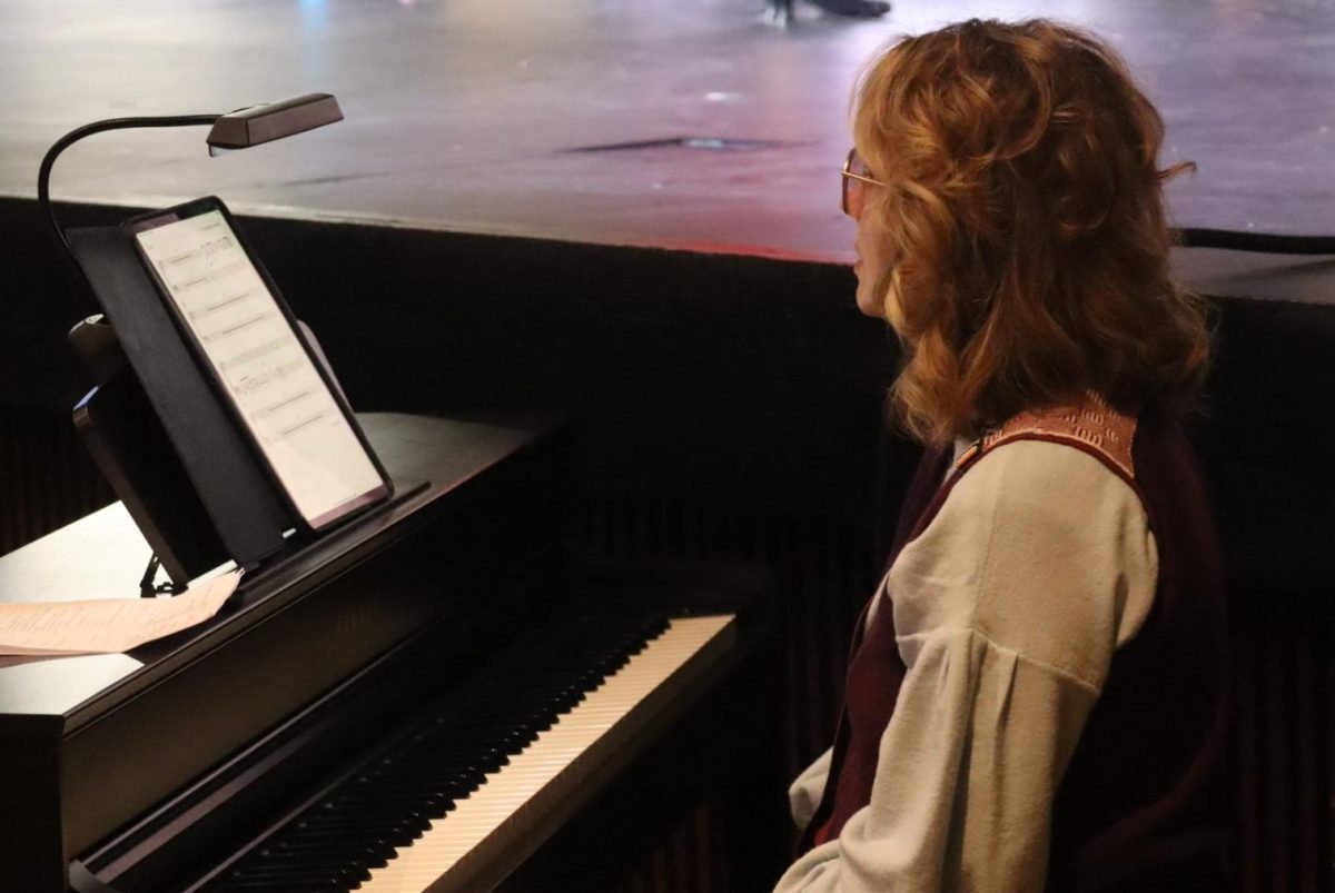 Waiting for her cue, professional pianist Kara Schofield watches the Orchestra Director, conductor Monika Bartley to come in at the right time. Schofield was hired to accompany the live pit orchestra and band for the show. The last show was supposed to happen tomorrow, but it was canceled due to no school with the icy roads.