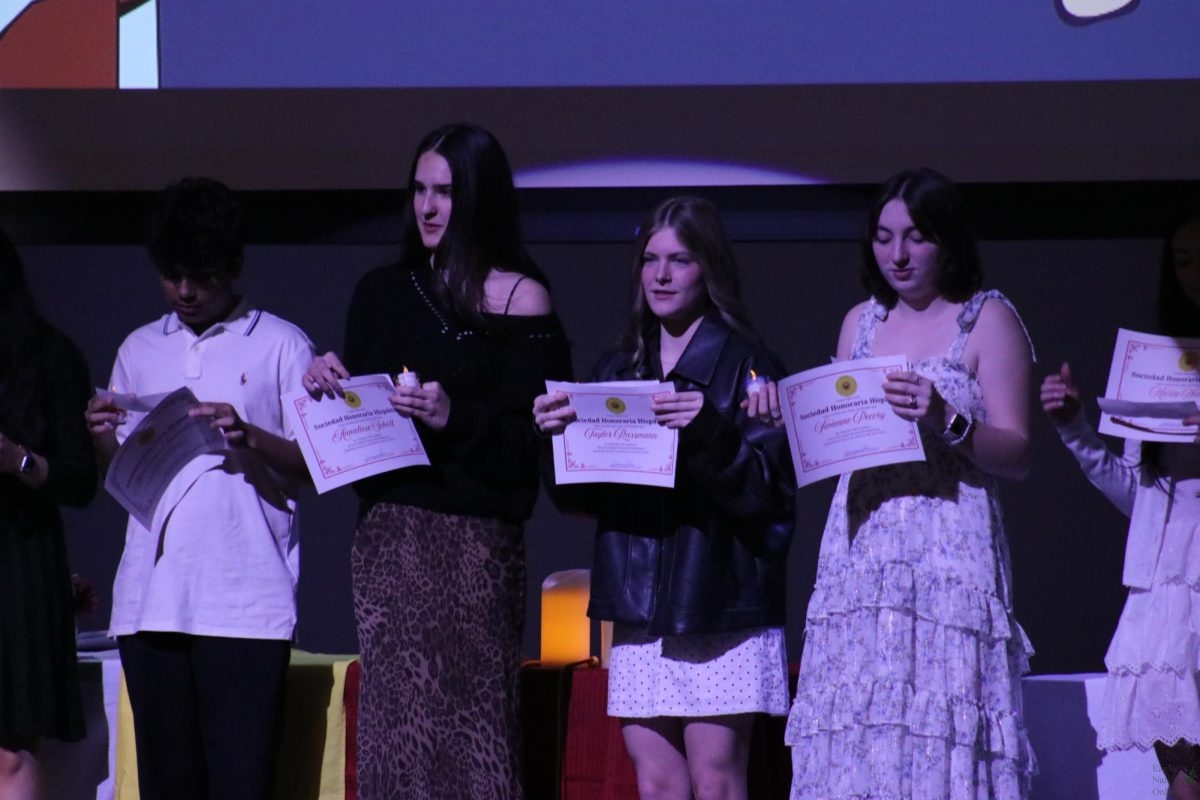 Standing on the auditorium stage, juniors Annaliese Schott, Taylor Russmann and Vivienne Pecory hold up their certificates. The Spanish Honor Society induction ceremony took place last Wednesday, Feb. 11. Francisco Salas is the adviser for the honor society.