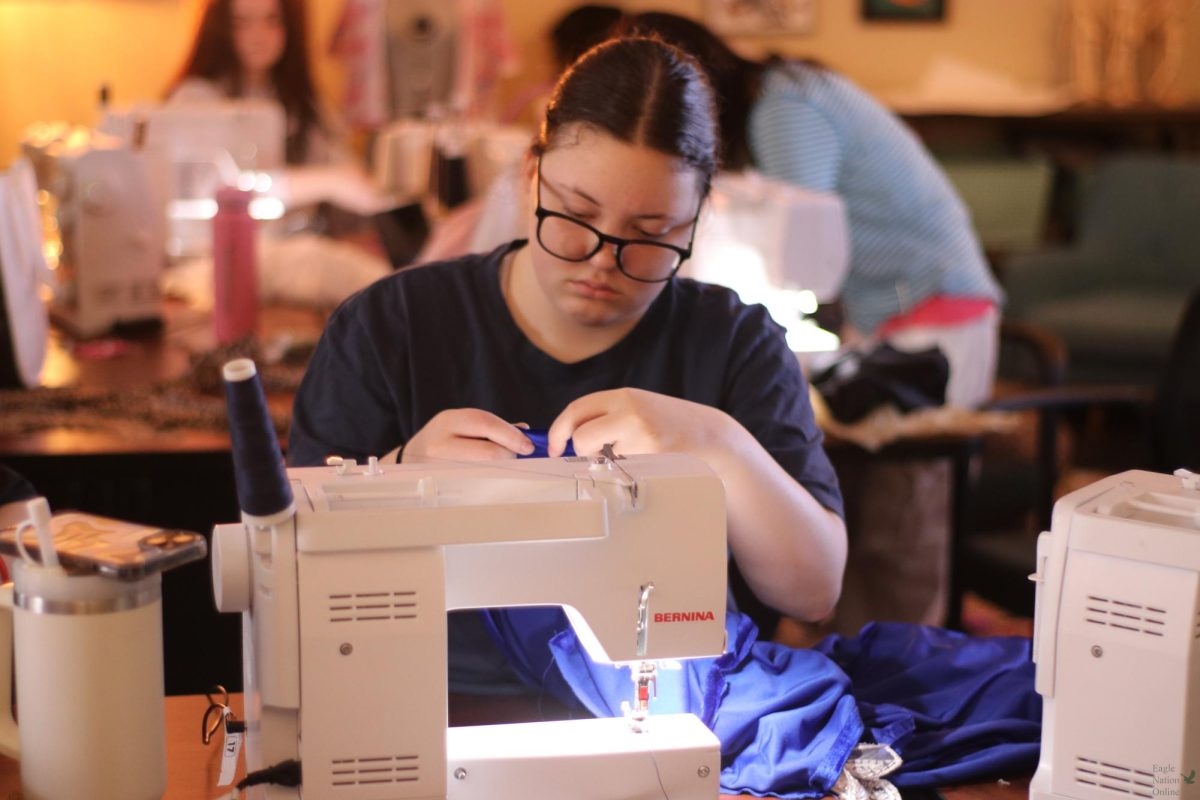 Curating stitches into fabric, senior Addison Monaco works on her design for the up coming fashion show. The event will occur in April. "I'm working on a blue dress," Monaco said. "This dress is for Aiden, she's part of the special needs program, and we're including her in the fashion show."