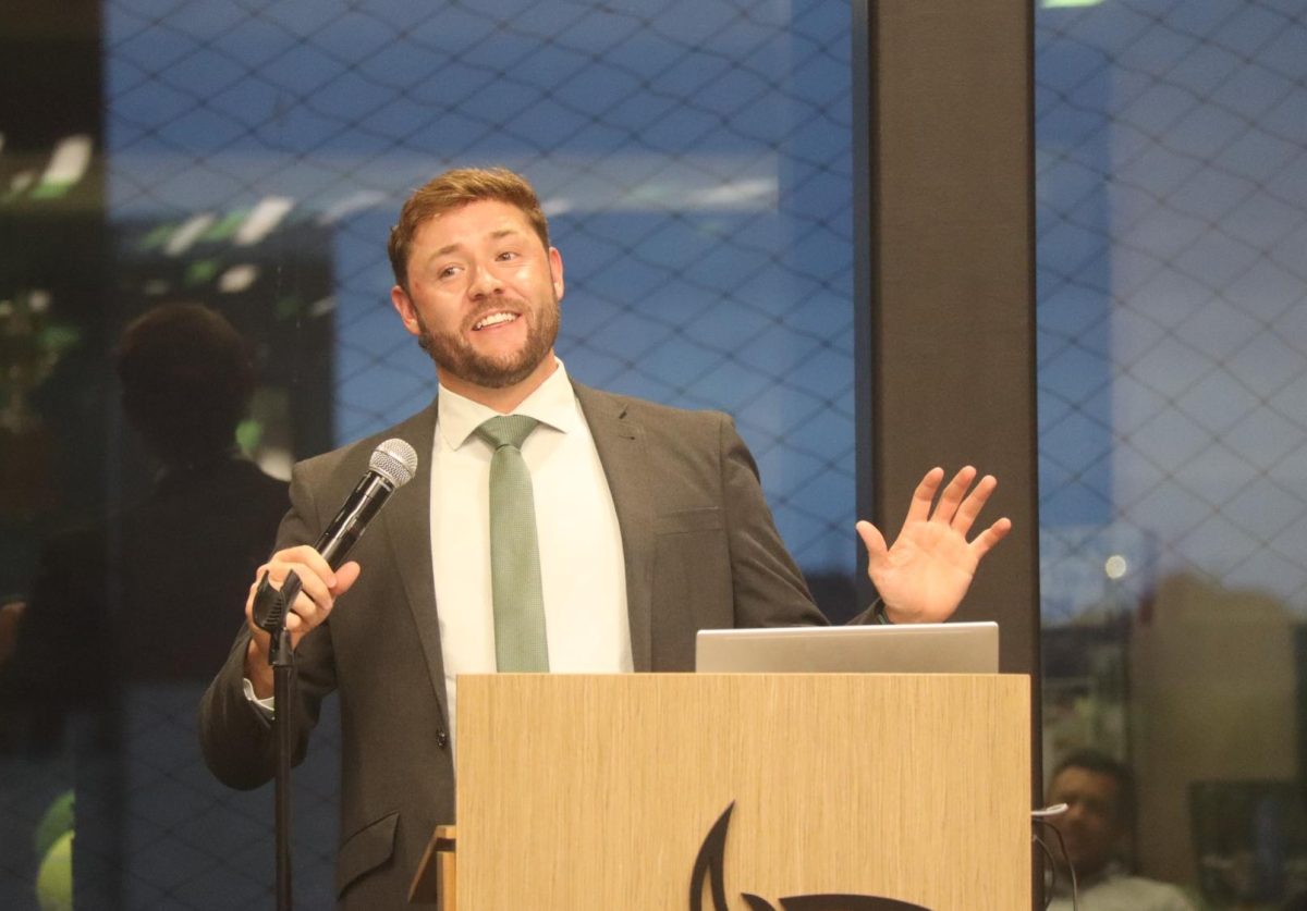 Holding a microphone, Head Tennis Coach Curtis Martin praises his tennis players at their banquet. The event took place Apr. 29 from 6-9 p.m. Both JV and Varsity teams were recognized by their coaches, peers and families.